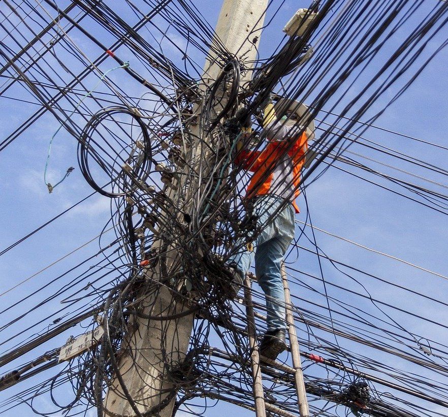 Poteau avec des câbles électrique, téléphoniques et cuivre avec un réparateur perdu