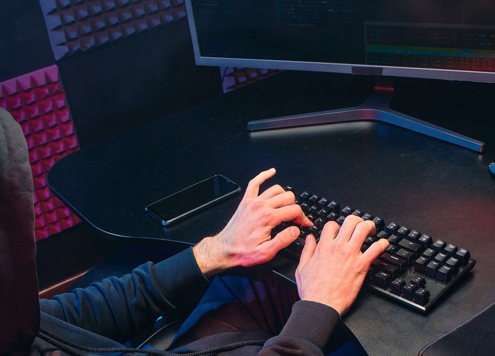 Un hacker tente de dérober des données depuis un ordinateur on voit ses mains sur un clavier