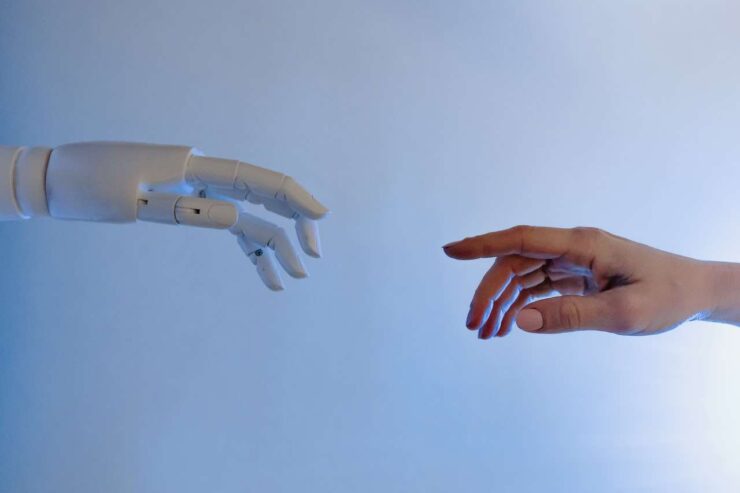 La main d'un robot intelligence artificielle se rapproche de la main d'un être humain : IA et ChatGPT (allégorie)